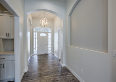 wide space with large windows, custom fireplace, ceiling fan, wooded floor, white ceiling and walls