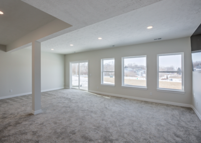 wide space with large windows, custom fireplace, ceiling fan, wooded floor, white ceiling and walls