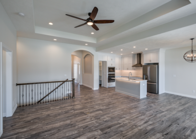 wide space with large windows, custom fireplace, ceiling fan, wooded floor, white ceiling and walls