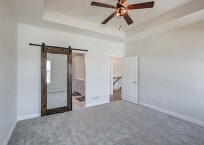 wide carpeted space with sliding barn door,bedroom ceiling fan, white walls and ceiling