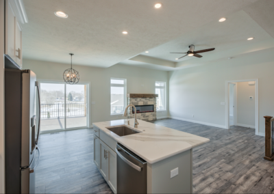 wide kitchen, kitchen island with sink, kitchen lights and ceiling fan, large windows, custom fireplace